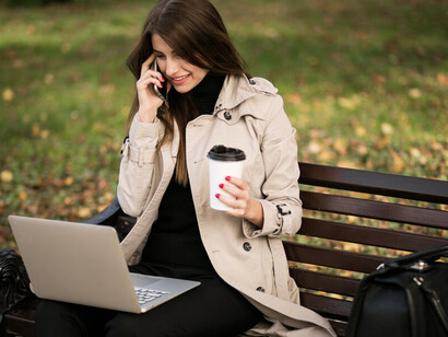 A businesswoman with a laptop in a park during autumn, reflecting on career planning and embracing the September transition