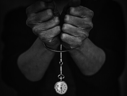 Hombre 'esposado' por un reloj colgante. Símbolo de la esclavitud del tiempo con la existencia