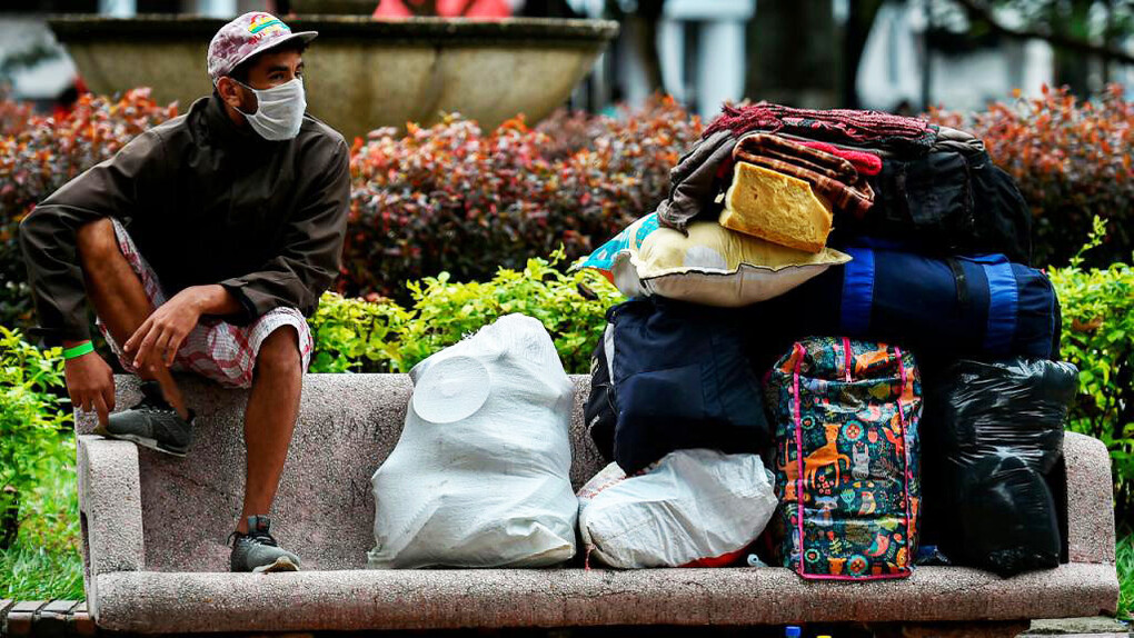 Migrante en un banco junto a sus escasa pertenencias en Santiago de Chile