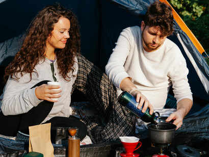 A young couple cooking on a portable kitchen during a camping trip