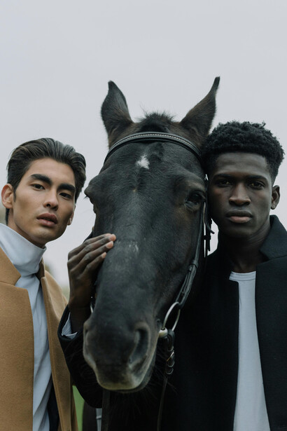 Young male fashion models posing beside a horse