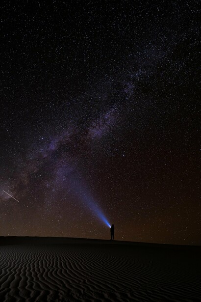 A figura iluminada contempla o universo como quem procura respostas muito além da Terra. O brilho da lanterna contrasta com a vastidão do céu, numa imagem que dialoga com a jornada solitária do protagonista. Observar as estrelas continua sendo um dos gestos mais humanos do cinema e da ciência