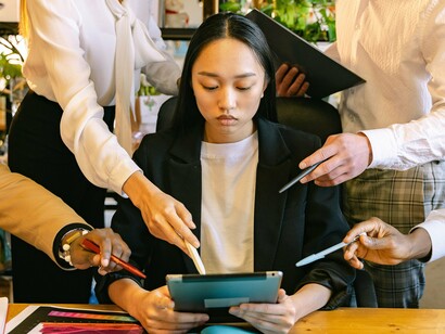 A young professional surrounded by colleagues offering guidance and feedback, representing workplace expectations and accountability