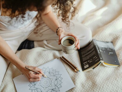 A person carefully filling in a mandala pattern with a coloring pen