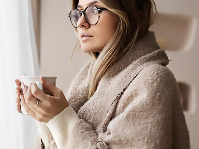 Amidst the winter chill, a woman donned in cozy attire relishes a moment with her coffee, finding comfort in every sip