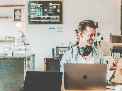 A man focused on his laptop, working in a bustling café setting