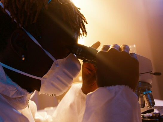 A scientist carefully examining a sample through a microscope, representing the pursuit of transcriptome research to advance human health