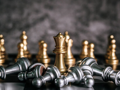 Gold and silver chess pieces on a chessboard, reflecting a mirrored game