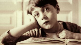 Un niño aburrido frente a un libro de texto