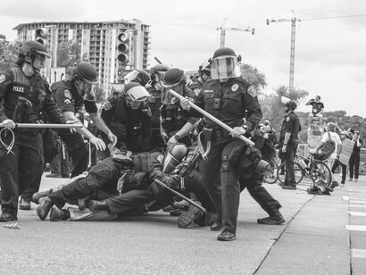 Police officers encircle a man lying on the ground, highlighting the imbalance of power