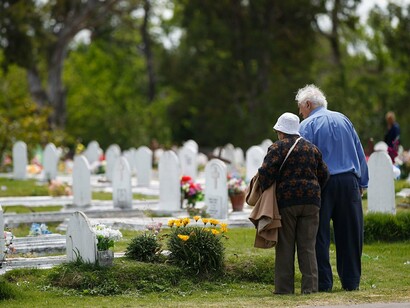 Un matrimonio de ancianos visita la tumba de un familiar