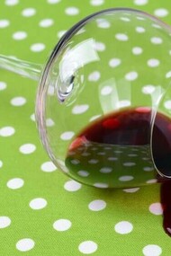 A glass of wine spilt on a brand new green and white polka dotted tablecloth
