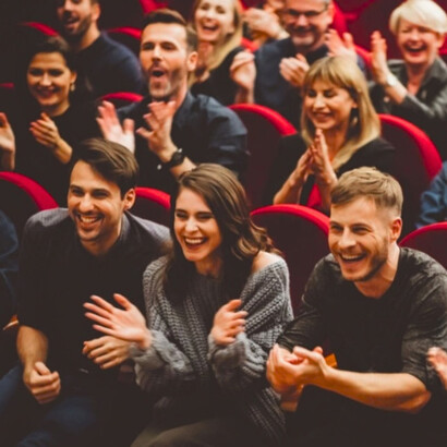 An audience laughing during a live performance, as they would during comedy Slugs
