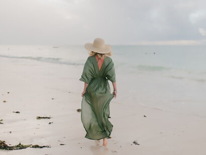 Woman walking along wet sandy beach in windy day