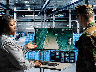 Military officer and defense analyst reviewing target coordinates at a command center