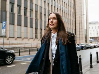 A woman in a black coat and scarf walking through the city street
