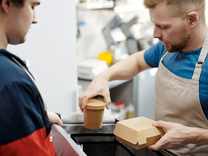 A man preparing eco-conscious food packages for delivery, utilizing mycelium, coffee waste, and smart packaging to reduce environmental impact