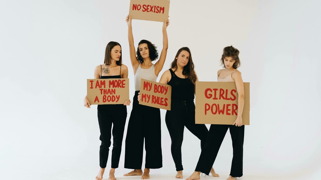 Women in black pants holding placards for women’s rights