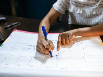 Mulher faz planejamentos em calendário. Ainda com a caneta na mão, ela olhou para os itens antigos rabiscados na agenda do ano
anterior. "Ler vinte livros", um clássico que terminava invariavelmente em um modesto
três, sendo dois de autoajuda