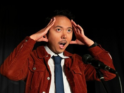 A performer under the spotlight, entertaining a crowd with stand-up comedy in an intimate comedy club