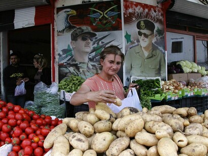 Una vendedora siria ante retratos de sus líderes