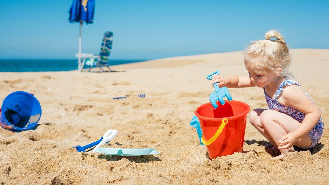 Menina brinca com areia na praia