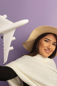 A woman with white scarf in summer hat showing toy airplan