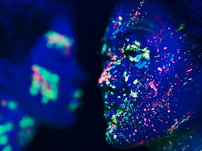 Intense close-up of woman with vivid fluorescent makeup, capturing abstract colors and evoking strong emotions