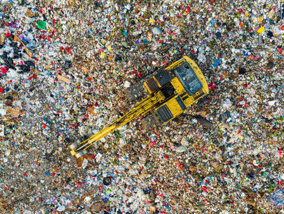 Vista aérea de una excavadora amarilla sobre montones de basura