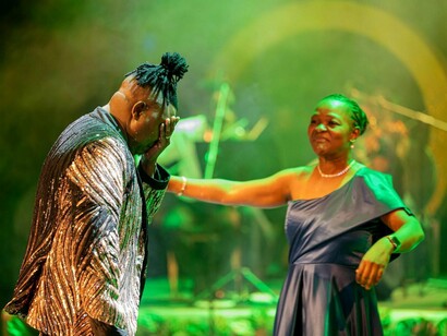Kika Materula aproxima-se de Nelson Tivane num instante de forte carga simbólica durante a apresentação. A parceria entre direção orquestral e repertório popular sustentou a identidade do concerto