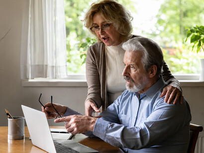 A distraught elderly couple receives shocking news on their computer after falling victim to online fraud