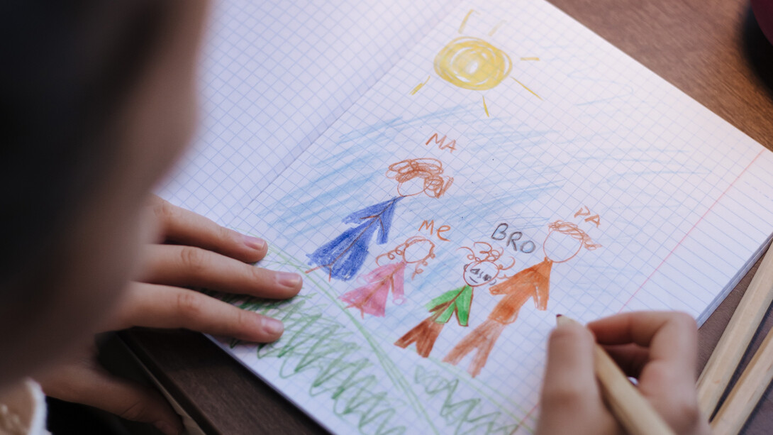 Lápis de colorir desliza pelo papel para criar desenho de uma família