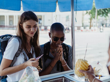 Women looking at and buying street food from a vendor in Asia