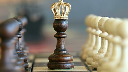 A chessboard with a pawn wearing a king’s crown, symbolizing growth, perseverance, and the journey to success