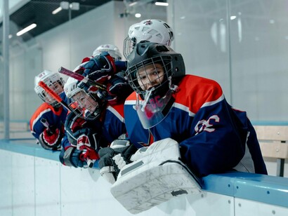 A boys’ ice hockey team watching from the stands, reflecting the transition from play to performance