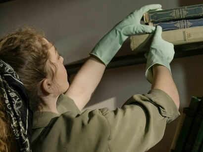 Une femme organise et nettoye l'étagère aux  livres