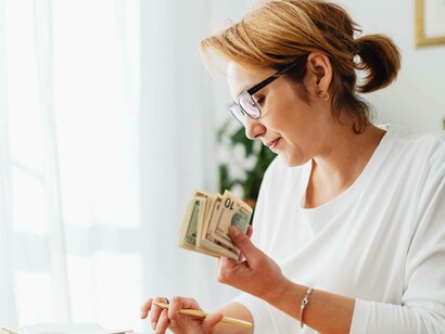 A woman counting money for her bills 