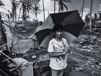 A survivor surrounded by shattered homes and fallen trees, reflecting the endurance in the face of devastation