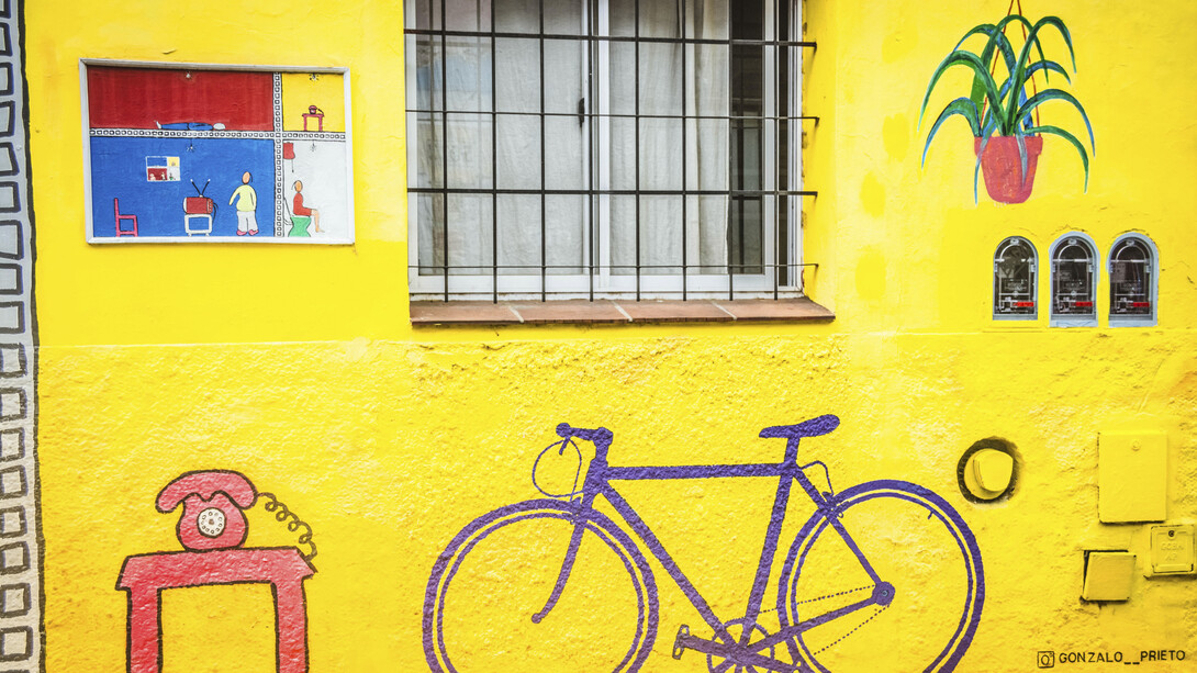 Bicicleta en el mural del artista Gonzalo Prieto, pintado en 2020, en el que se muestran las distintas partes de una casa en un vibrante color amarillo