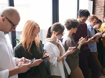 Pessoas lado a lado consultam seus celulares, concentradas em diferentes conteúdos enquanto compartilham o mesmo ambiente. O “olho no olho” dá lugar ao “olho na tela”, e a convivência cotidiana passa a acontecer sem necessariamente produzir encontro