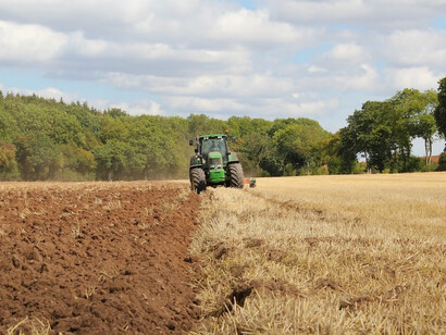 In the midst of the brown field, contrasted by the vibrant green, sits the farming equipment, Hohenberg-Krusemark, Germany