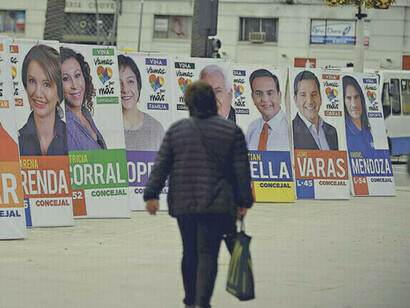 Eine Frau geht in Santiago, Chile, durch eine Straße voller Wahlpropaganda