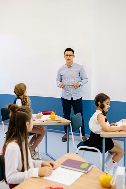 Teacher stands against the wall in a classroom with students