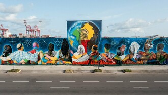 "Coexistence", de Eduardo Kobra, em Cotonou, na República do Benim em 2023. O mural reúne 12 figuras de costas, representando diferentes religiões, unidas diante de um globo que destaca a África e duas mãos entrelaçadas. Realizada na fachada do antigo Hotel do Porto, a obra ocupa cerca de 700 m² e transforma o espaço urbano em uma mensagem visual de tolerância, diálogo inter-religioso e convivência, reafirmando a presença internacional da arte urbana brasileira