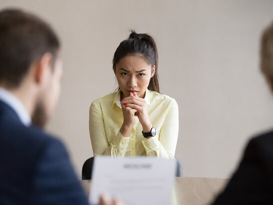 Young professional facing anxiety and pressure during a formal job interview in a modern office setting