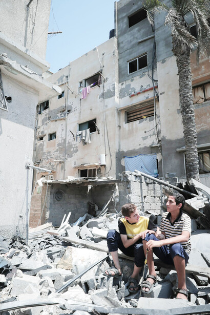 Two young men on a heap of rubble in a residential complex in Gaza, Palestine