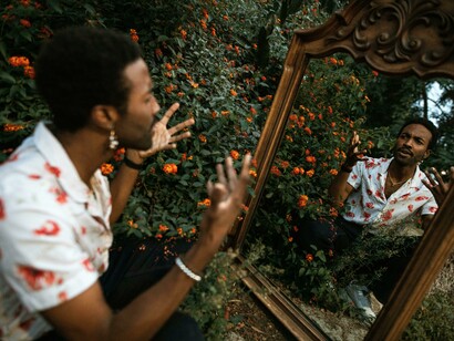 An isolated young man confronting himself in the mirror, reflecting the psychological strain of secrecy, self-doubt, and fractured identity