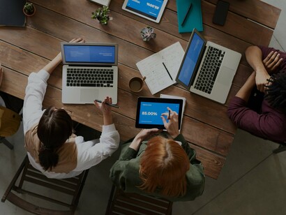 People discussing at a table with laptops