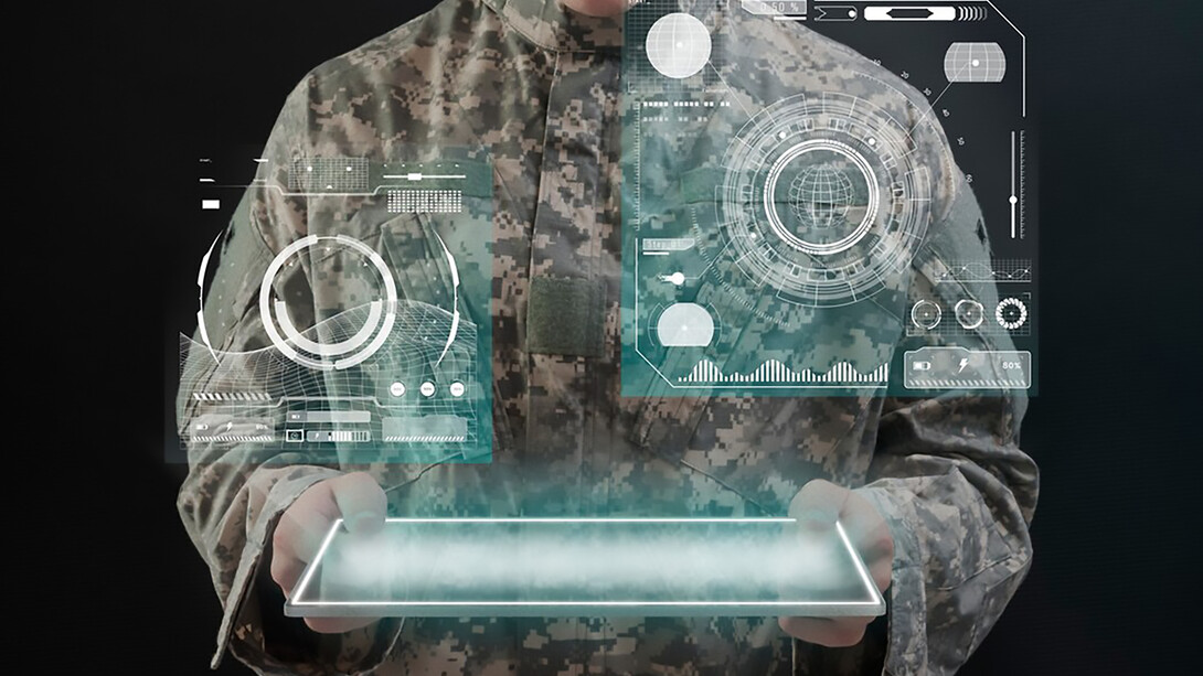 A soldier using a virtual tablet hologram represents the integration of advanced technology in military operations, highlighting the importance of military spending, global security, and economic power in shaping defense budgets