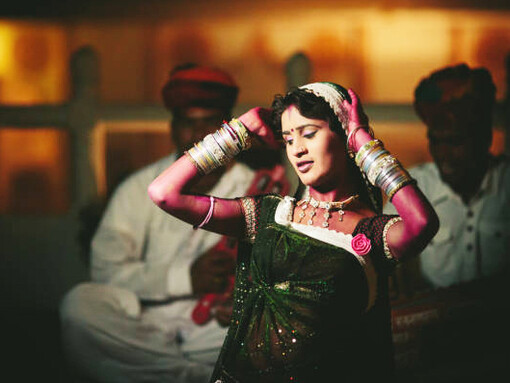 A Bollywood actress dressed in a traditional Indian outfit adorned with gold jewelry, standing on a film set with a cinematic landscape in the background, as a Bollywood film crew captures the scene